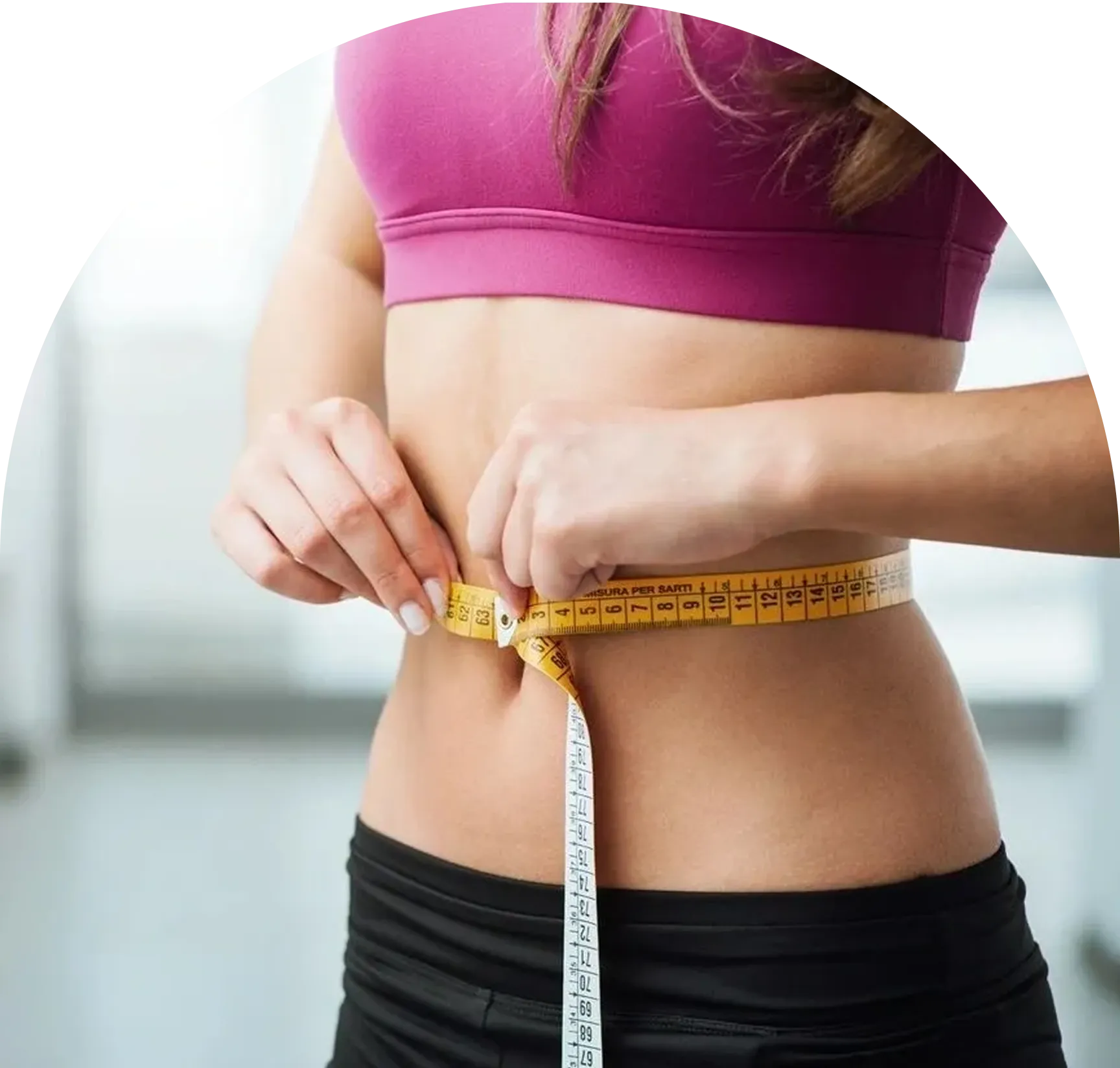Woman measuring waist with yellow tape measure.